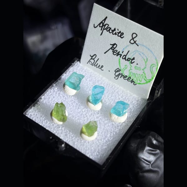 Blue apatite and green peridot crystals in a small display box — alternate view