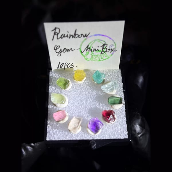 Ring of ten rainbow gem rough crystals in a mini display box — complete view
