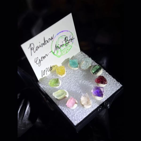 Ring of ten rainbow gem rough crystals in a mini display box — alternate view