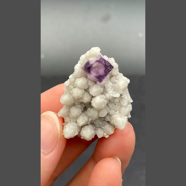 Deep purple fluorite crystal among white quartz balls from Inner Mongolia — alternate view