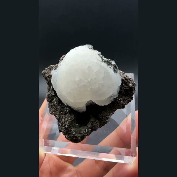 White stilbite ball on dark basalt from Aurangabad, India — complete view