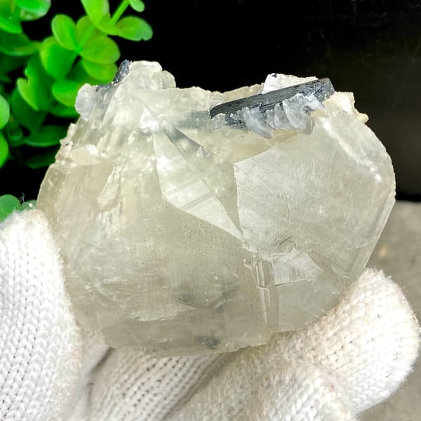 Glassy calcite crystal with dark metallic stibnite blades — alternate view