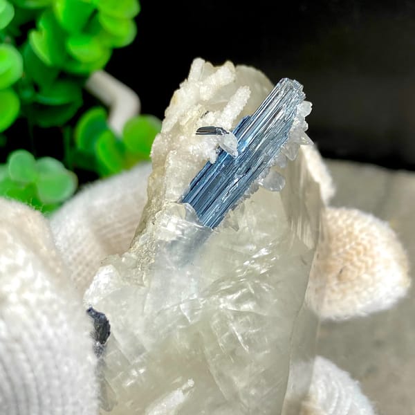 Glassy calcite crystal with dark metallic stibnite blades — detail view