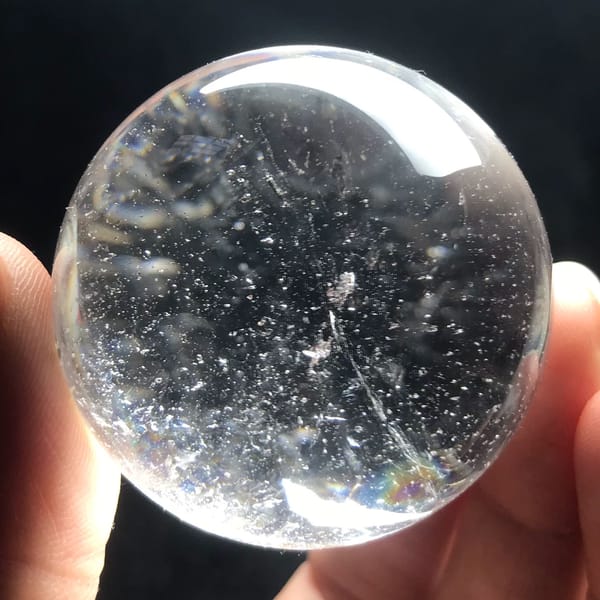 Small clear quartz sphere with dark tourmaline inclusions from Brazil — alternate view