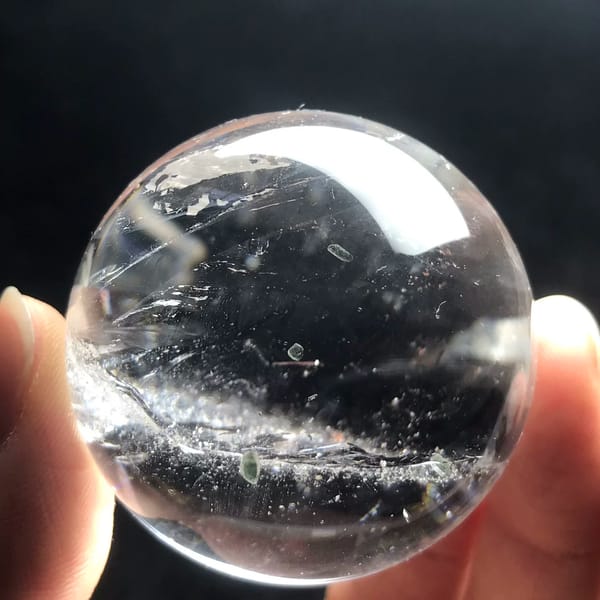 Small clear quartz sphere with dark tourmaline inclusions from Brazil — alternate view