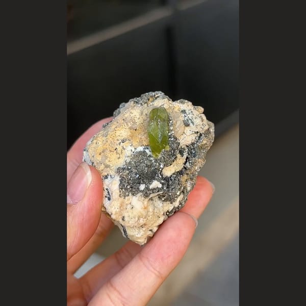 Green titanite twin crystal with mica and feldspar from Pakistan — detail view