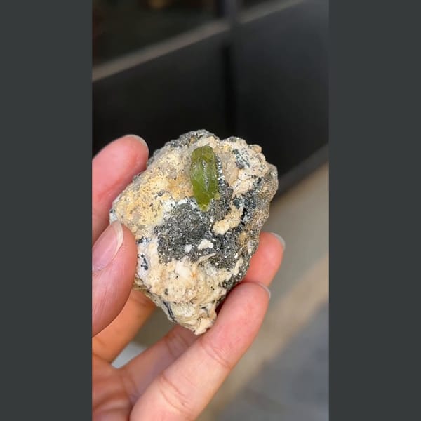 Green titanite twin crystal with mica and feldspar from Pakistan — detail view