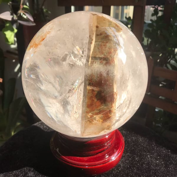 Clear quartz sphere with a thick golden included rod from Brazil — complete view