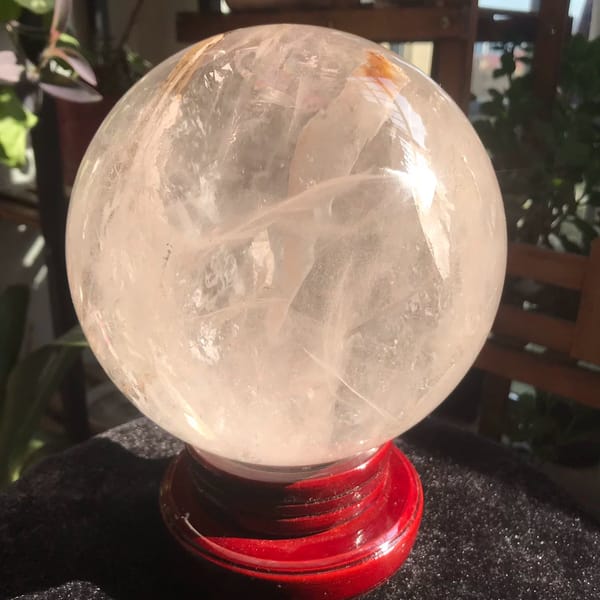 Clear quartz sphere with a thick golden included rod from Brazil — alternate view