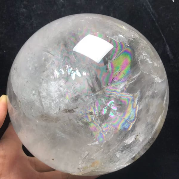 Clear quartz sphere with a thick golden included rod from Brazil — detail view
