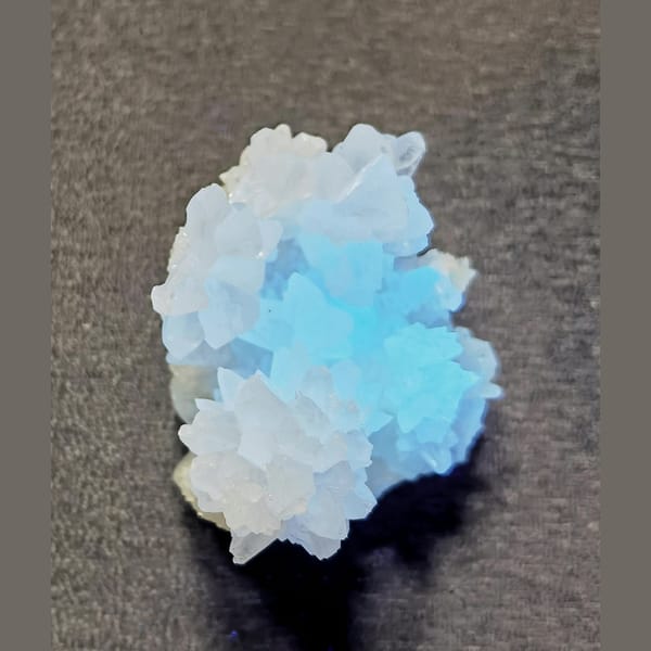 White cauliflower calcite flower with cyan UV glow — detail view