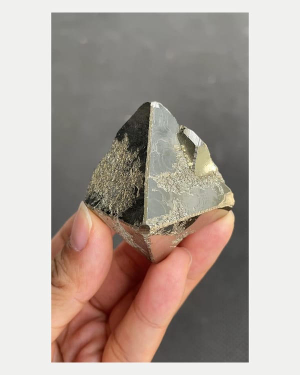 Complete pointed front view of mirror-bright Peruvian pyrite crystal