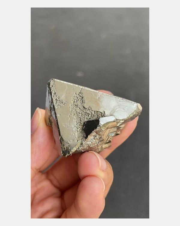 Complete side view of triangular pyrite face and rough underside