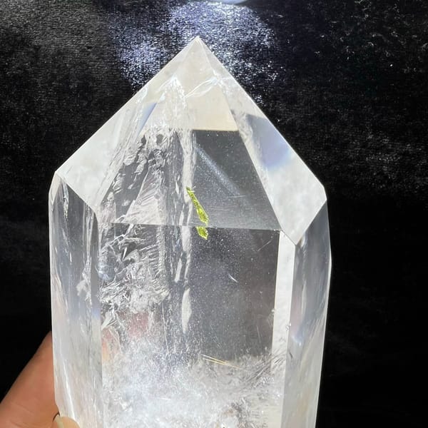 Clear quartz point with enclosed green tourmaline and white phantoms — detail view
