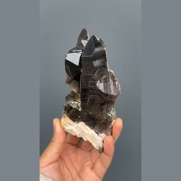 Tall near-black morion smoky quartz on cream feldspar from Wulian, Shandong — complete view