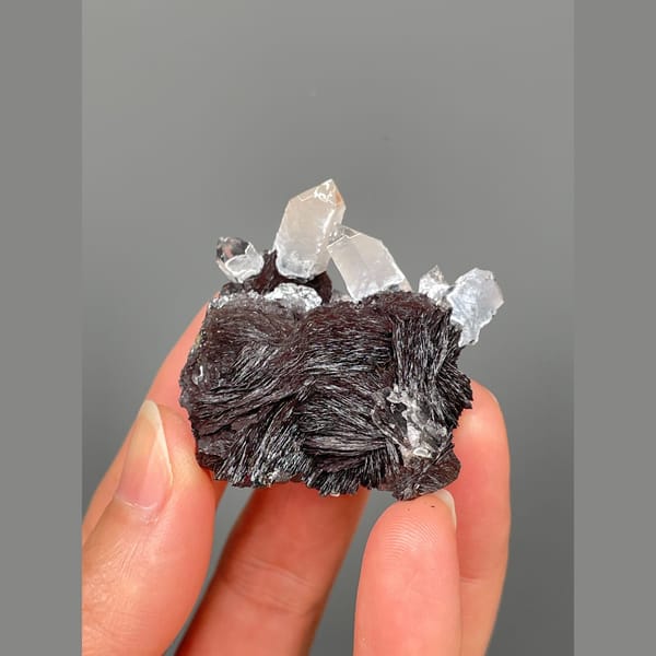 Clear quartz points on lustrous specular hematite from Guangdong — alternate view