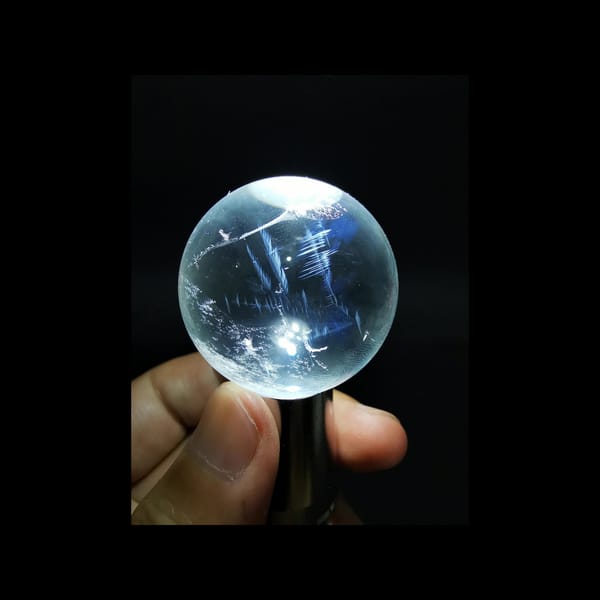 Clear quartz sphere with blue needle inclusions — complete view