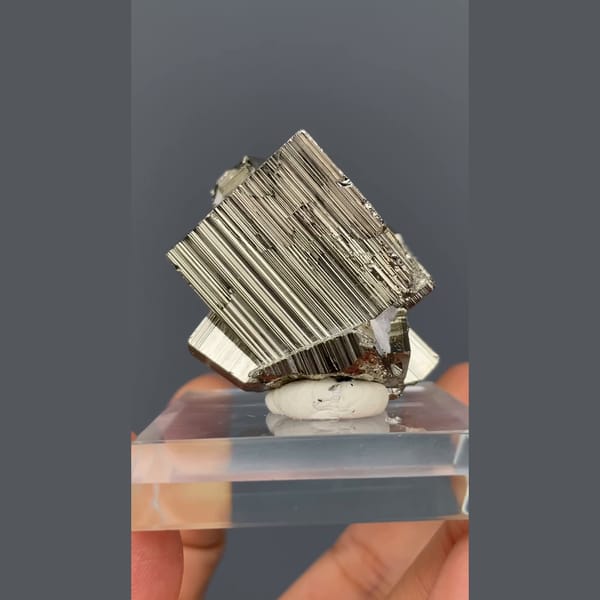Bright striated cubic pyrite crystals from Peru on a clear stand — complete view