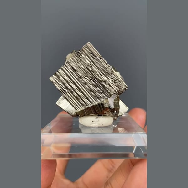Bright striated cubic pyrite crystals from Peru on a clear stand — detail view