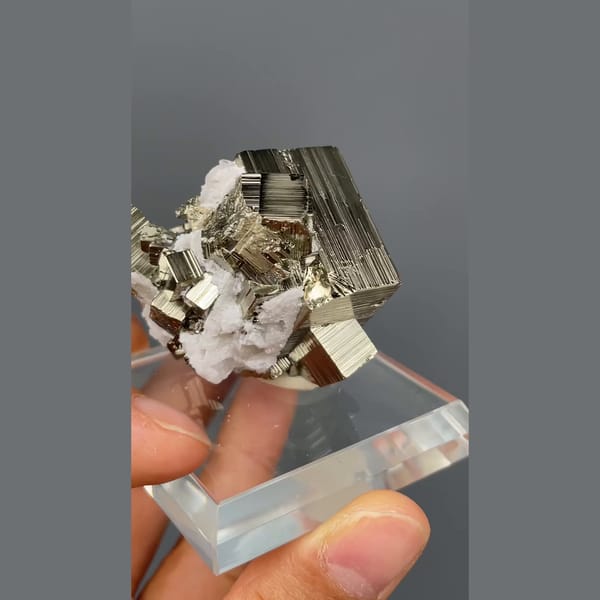 Bright striated cubic pyrite crystals from Peru on a clear stand — detail view