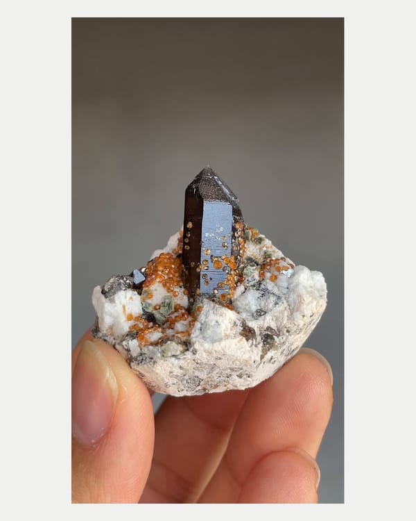 Complete front view of smoky quartz with spessartine and feldspar