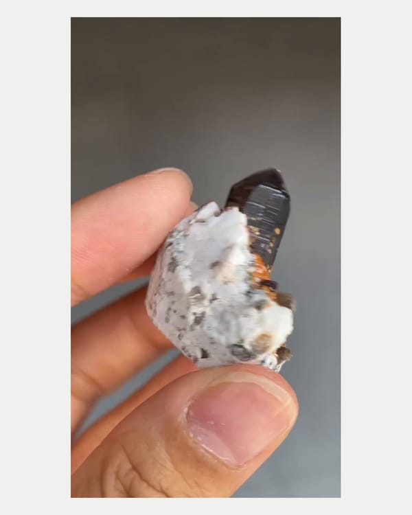 Complete right oblique view of smoky quartz with spessartine and feldspar