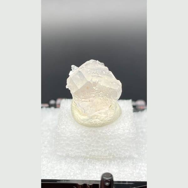 Tiny colourless fluorite crystal with mica from Pakistan — complete view