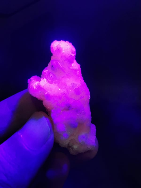 Pale pink calcite floater cluster under ultraviolet light, fluorescence view