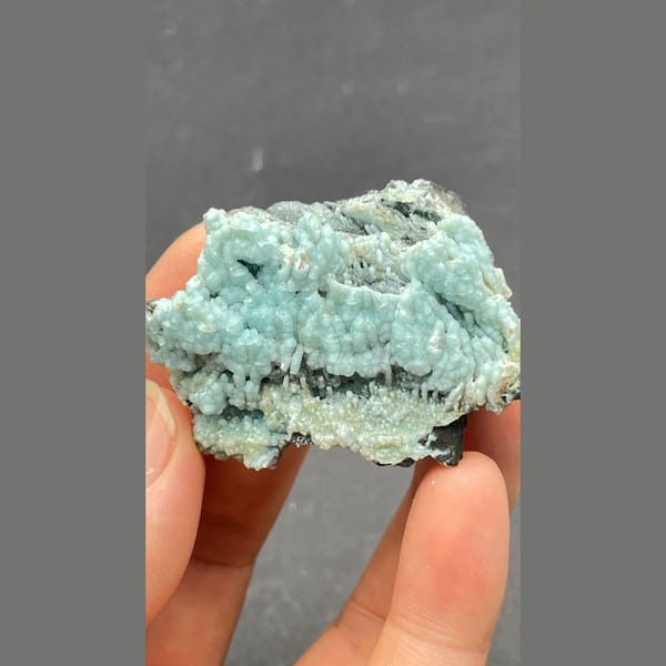 Botryoidal blue-green gibbsite crust on dark matrix from Yunnan — detail view
