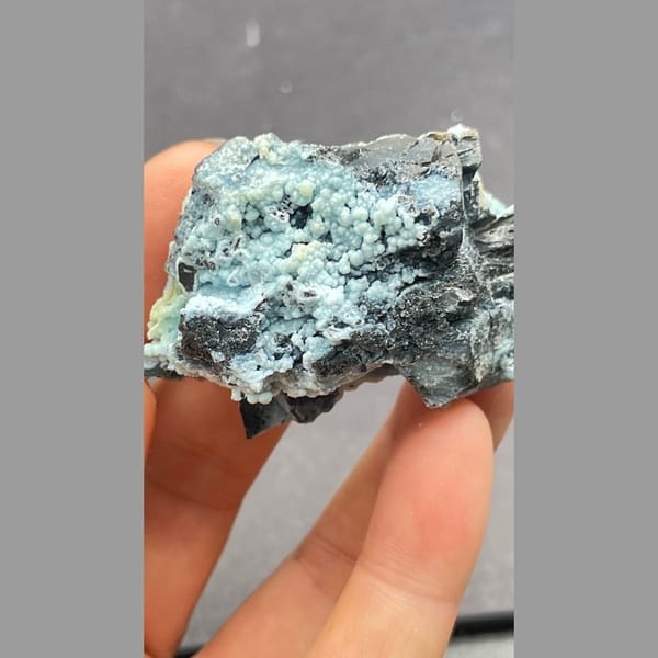 Botryoidal blue-green gibbsite crust on dark matrix from Yunnan — detail view