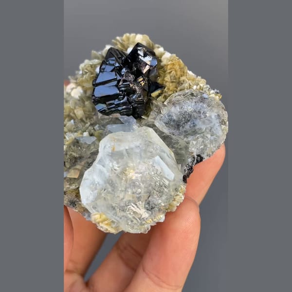 Black cassiterite with pale aquamarine on mica from Xuebaoding, Sichuan — alternate view