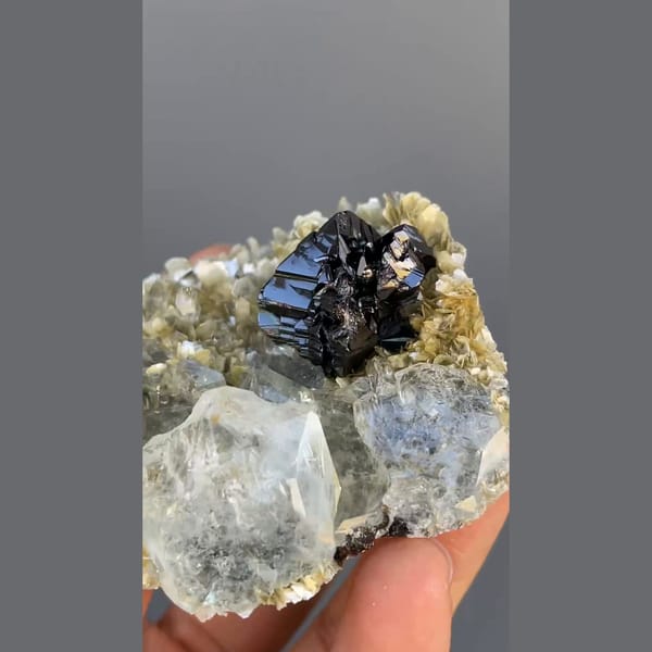 Black cassiterite with pale aquamarine on mica from Xuebaoding, Sichuan — detail view