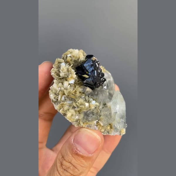 Black cassiterite with pale aquamarine on mica from Xuebaoding, Sichuan — detail view