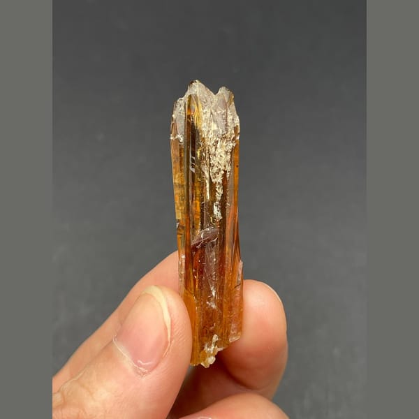 Slender glossy amber calcite crystal from Guizhou — complete view