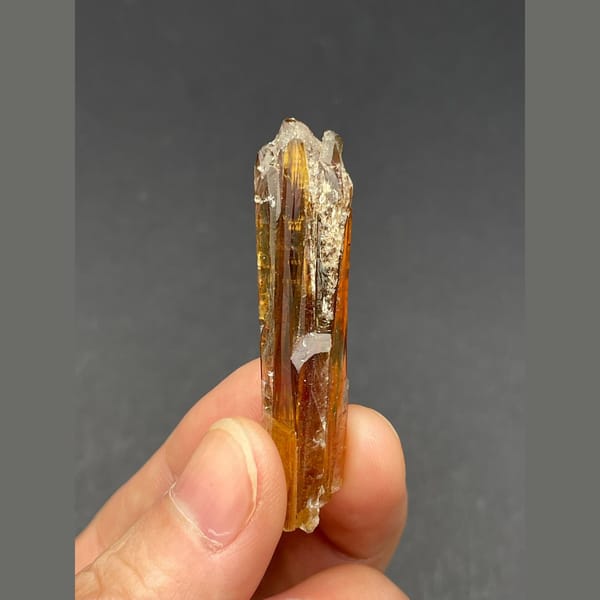 Slender glossy amber calcite crystal from Guizhou — alternate view