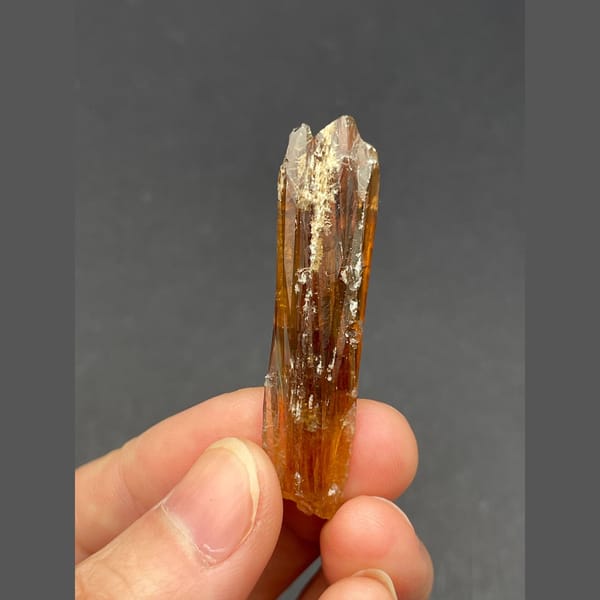 Slender glossy amber calcite crystal from Guizhou — alternate view