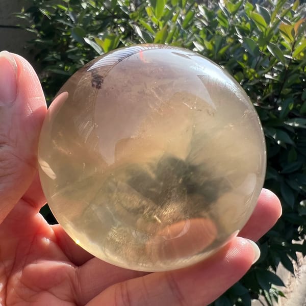Citrine ball showing a small smoky patch near the base among white fibres