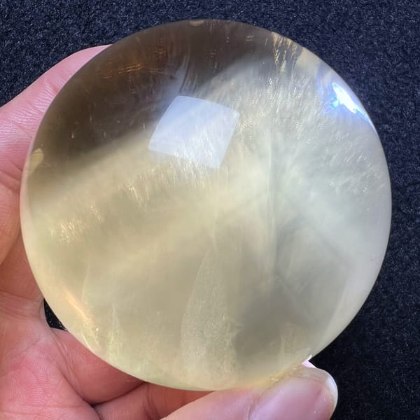 Citrine sphere on dark cloth with white Rutilated streaks fanning out
