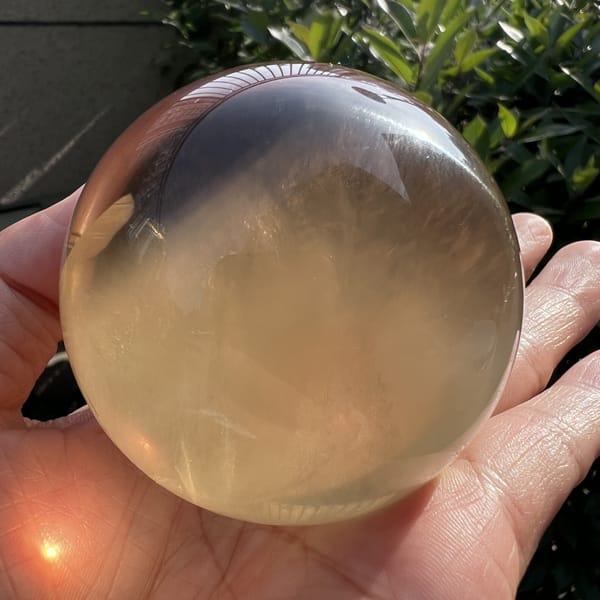 Citrine sphere with a dark reflection band and pale wispy interior