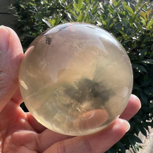 Smoky cloud and honey glow inside the citrine sphere against leaves