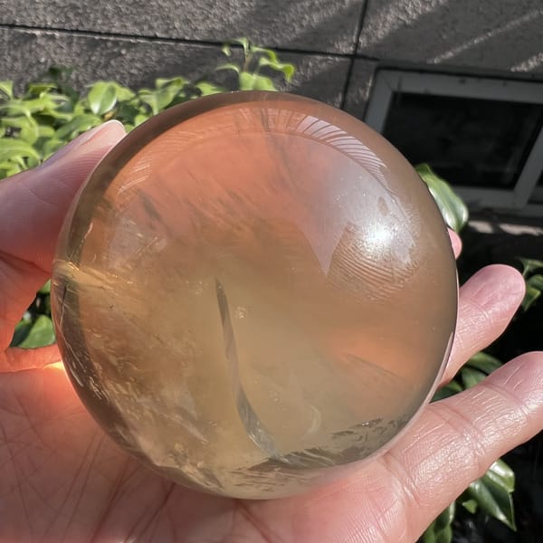 Citrine sphere in front of a wall showing a clear honey body and inner veil