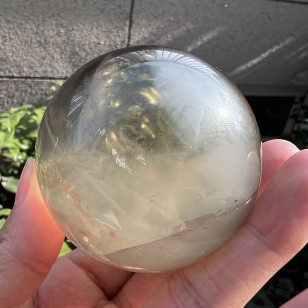 Citrine sphere with a greenish-gold interior and white haze at the base