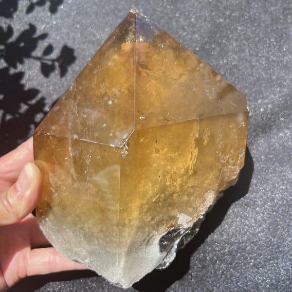 Golden citrine point with phantom layers visible beneath the polished tip
