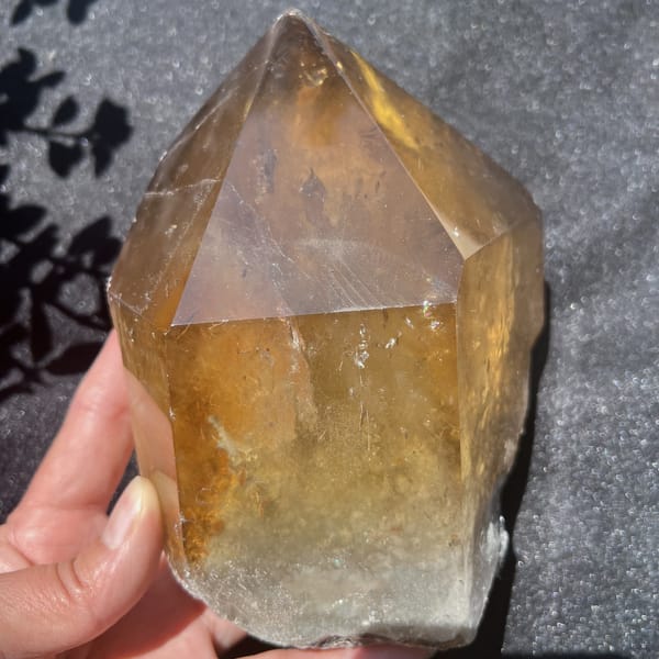 Citrine held upright with deep gold colour fading to smoky white at the base