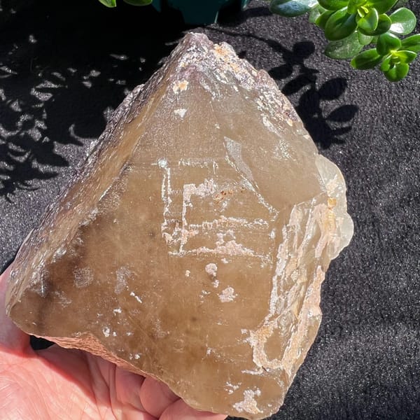 Citrine point with white growth lines tracing an earlier crystal outline