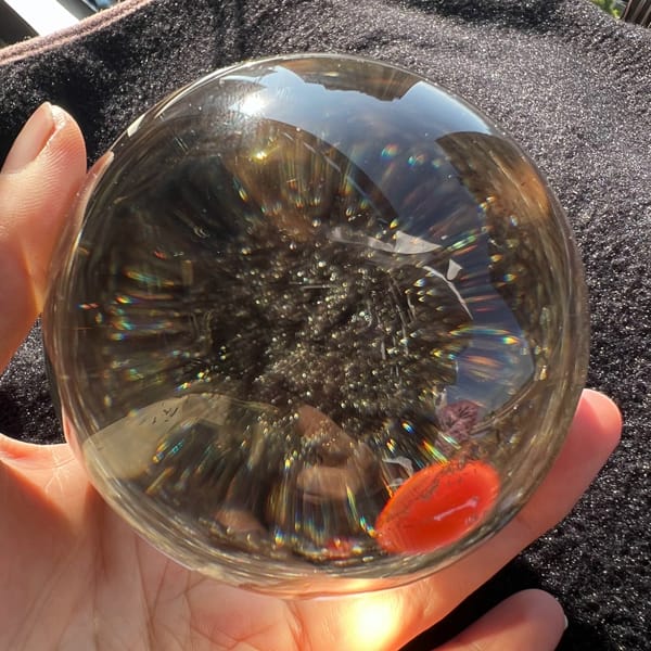 Cloud of black-silver rutile hanging inside the clear citrine sphere
