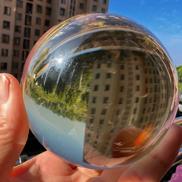 Citrine sphere outdoors reflecting an inverted apartment block and trees