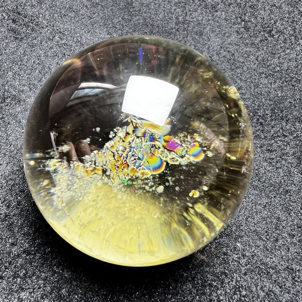 Citrine sphere with violet and gold rainbow rings in the inclusion band