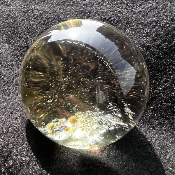 Citrine sphere on dark cloth with a rainbow at the lower edge