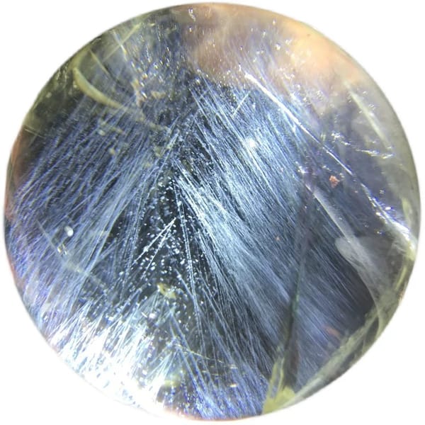 Close view of overlapping blue needles and tiny bubbles in the citrine